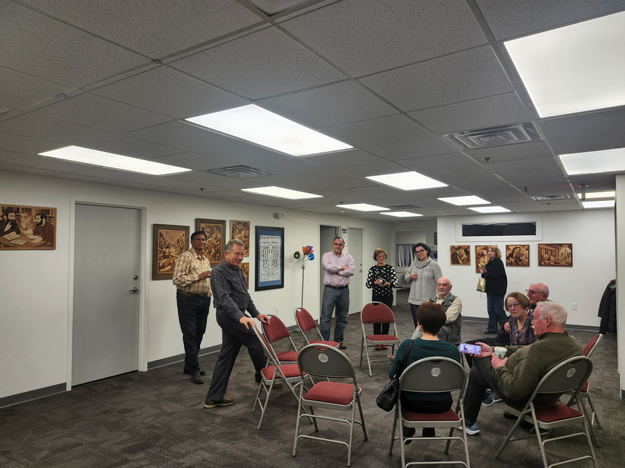Visitors gathered during the opening of Fragments of Memory exhibition, engaging with marquetry works displayed on the walls